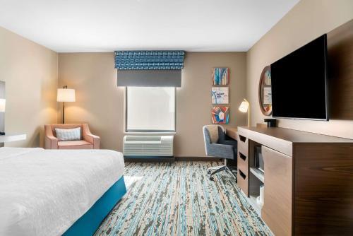 a hotel room with a bed and a flat screen tv at Hampton Inn Detroit/Auburn Hills-North in Auburn Hills