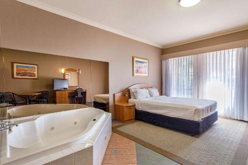 a bedroom with a bed and a bath tub and a bed at Quality Inn Penrith Sydney in Penrith