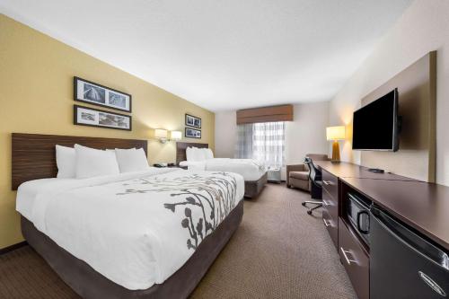 a hotel room with two beds and a flat screen tv at Sleep Inn & Suites West-Near Medical Center in Rochester