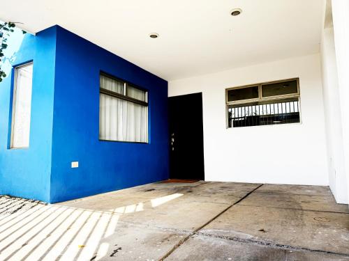 an empty room with a blue wall and windows at Casa Matiza, 7 min SJO airport, free parking, AC in Santiago Este