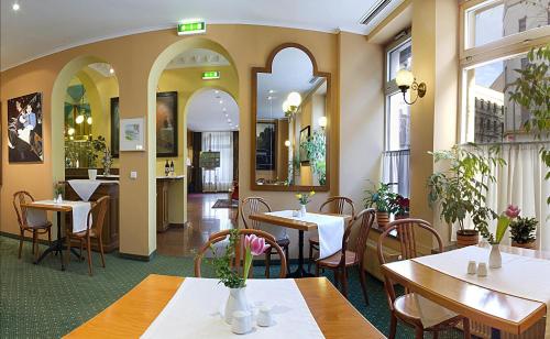 a restaurant with tables and chairs and windows at Galerie Hotel Leipziger Hof in Leipzig