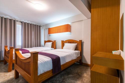 a hotel room with two beds and a desk at XX GO INN Khaosan ข้าวสาร กรุงเทพมหานคร in Bangkok