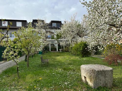 een tuin met een stenen bank en bloeiende bomen bij Ferienwohnung Gabriel in Rust