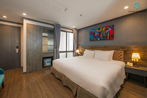 a bedroom with a large white bed and a fireplace at Solare De Monte Hotel & Spa in Hanoi