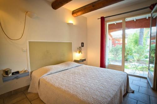 une chambre avec un lit et une grande fenêtre dans l'établissement La Bastide des Pins, à Castillon-du-Gard