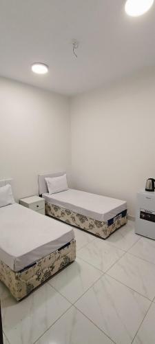 two beds in a room with white walls at عمارة دانة بنت أحمد Dana Bint Ahmed in Al Madinah