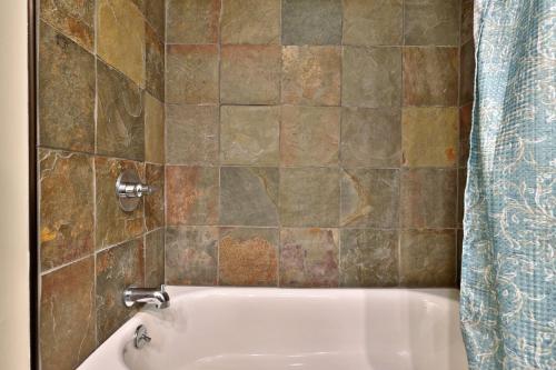 a bathroom with a bath tub with a tiled wall at Tranquil Peaks Studio at KCIS - Perfect for a Getaway in the Heart of Vermont Ski Resort in Killington