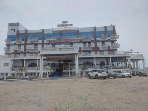 a large building with cars parked in front of it at Hotel Yathin in Mysore