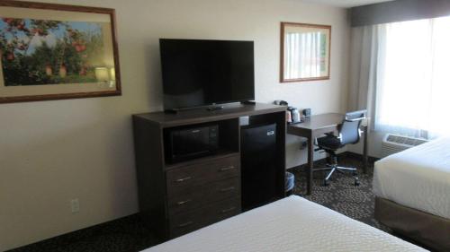 a hotel room with a television on a dresser with a desk at Clarion Pointe Wenatchee in Wenatchee