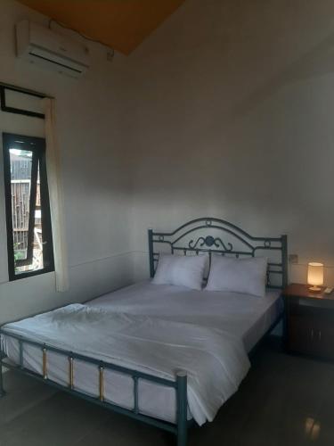 a bedroom with a bed with white sheets and a window at D' La Calma Guest House in Selong
