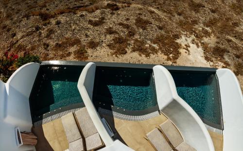 a swimming pool with two chairs in front of it at Aegean Blue Suites in Pirgos