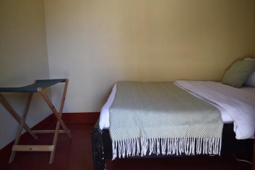 a small bedroom with a bed and a chair at Stasumo House Arusha in Arusha