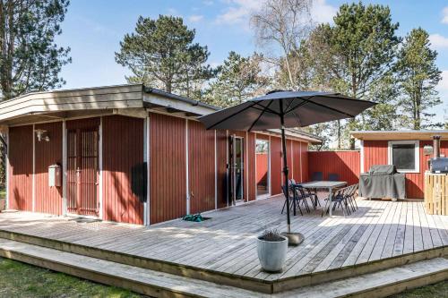 a house with a deck with a table and an umbrella at Family-Friendly Cottage Close To The Water in Nykøbing Sjælland