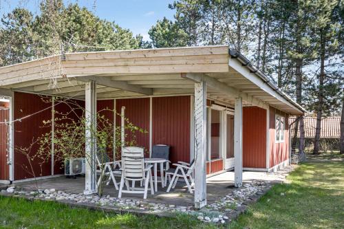 awning over a porch of a red house with a table and chairs at Family-Friendly Cottage Close To The Water in Nykøbing Sjælland