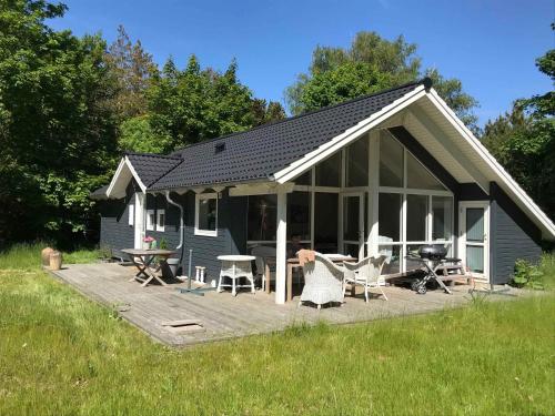 a blue house with a deck with chairs and tables at Newer Holiday Home In Green Surroundings in Jægerspris