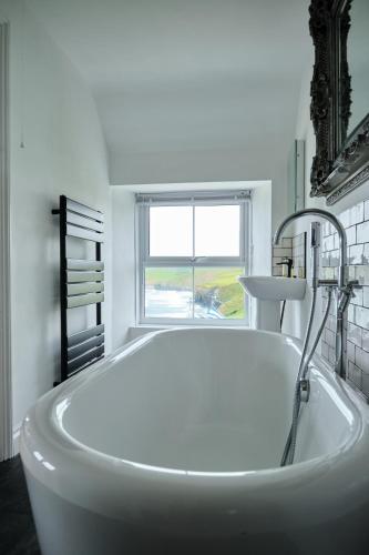 a white bath tub in a bathroom with a window at Beacon Crag in Porthleven