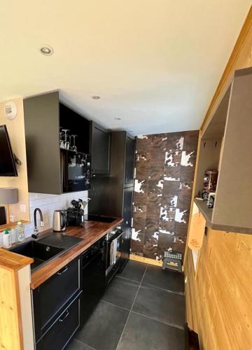 une cuisine avec des armoires noires et un comptoir dans l'établissement Bel Alp, cosy au pied des pistes, à Les Deux Alpes