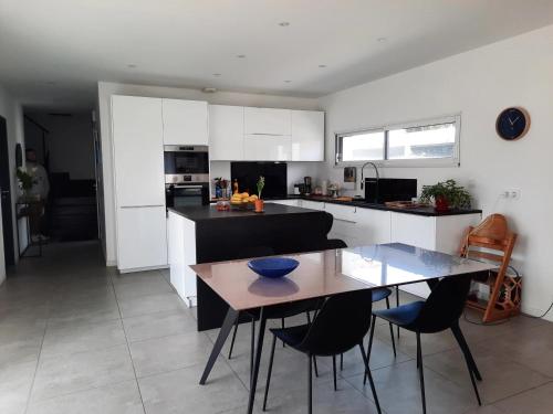 une cuisine avec une table et des chaises dans une pièce dans l'établissement Maison contemporaine 3 chambres, à Anglet