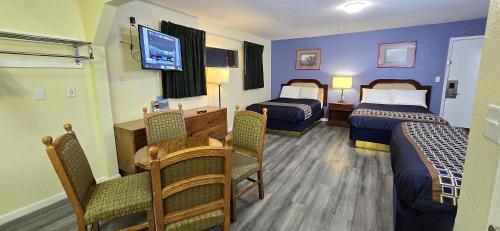 a hotel room with two beds and a table and a dining room at Rodeway Inn & Suites Blythe I-10 in Blythe