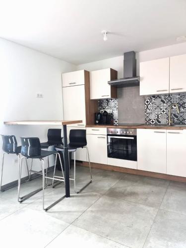 a kitchen with white cabinets and a table and chairs at Start appart in Village-Neuf