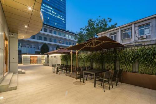 a patio with tables and chairs and umbrellas at Dequan Luxury Hotel CBD BranchCoffee, fruits, snacks, a gym and a laundry room are provided for free in the lobby in Beijing
