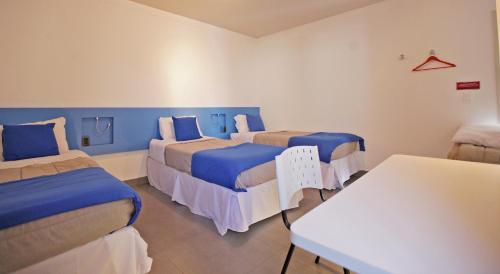 a hospital room with three beds and a table at Concept Design Hostel & Suites in Foz do Iguaçu