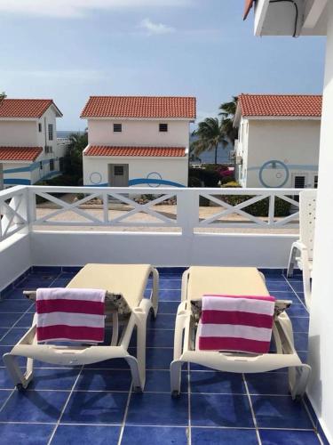 two chairs on a balcony with a view of a house at Little Slice of Paradise in Westpunt