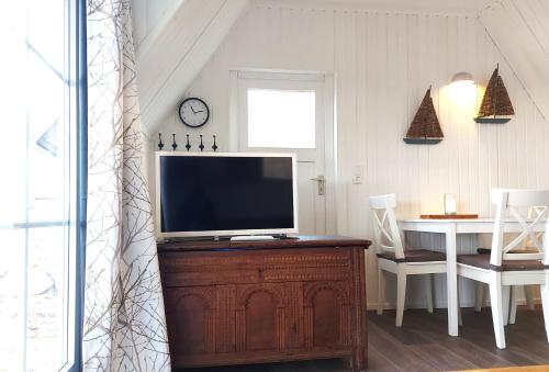 a living room with a television on a wooden dresser at Vier Winde Usedom - Ferienanlage in Krummin
