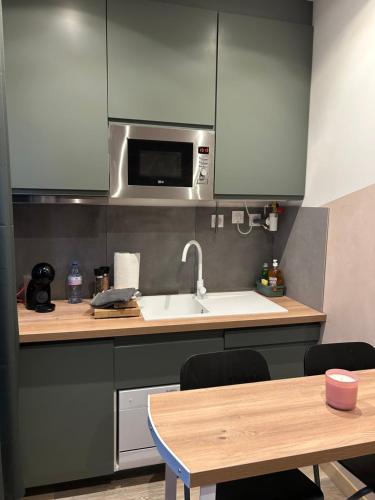 Il comprend une cuisine équipée d'un évier, d'un four micro-ondes et d'une table. dans l'établissement Appartement Savane entre Disney et Paris, à Lagny-sur-Marne