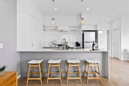 a kitchen with white walls and a counter with stools at Stylish 3BR Townhouse CampHill - WiFi, Parking in Brisbane
