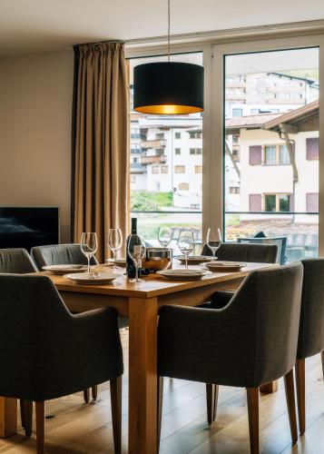 a dining room table with chairs and a large window at Kühtai Alpensuites in Kühtai