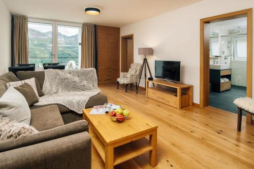 a living room with a couch and a table with a bowl of fruit at Kühtai Alpensuites in Kühtai
