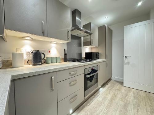 a kitchen with white cabinets and a stove top oven at Stylish 2 Bedroom Home Near Lake with Free Parking & Garden in Doncaster