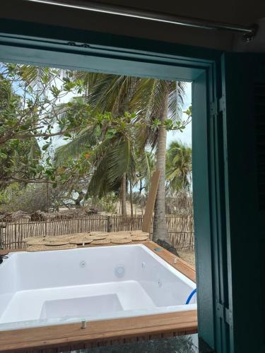 a bath tub in a room with a palm tree at Casa Pé na Areia, Jacuzzi e Natureza in Atins