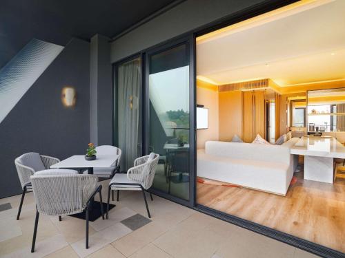 a living room with a bed and a table and chairs at Chengdu Expo Waterfall Hotel - MGallery Collection in Chengdu