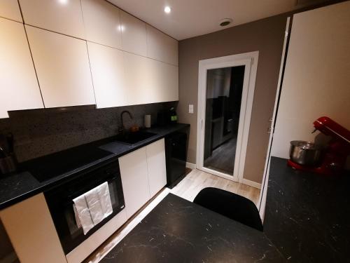 une cuisine avec des armoires blanches et un comptoir noir dans l'établissement L'Azur - Apt 4 Prs avec jardin en centre ville, à Dijon
