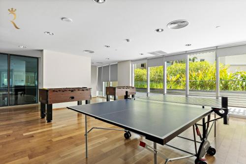 a ping pong table in a room with windows at Oasis Stylish 2BR in Al Rahba - Modern Stay Near Al Raha Beach & Yas Island in Yas Island