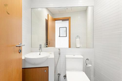 a bathroom with a sink and a toilet and a mirror at Oasis Stylish 2BR in Al Rahba - Modern Stay Near Al Raha Beach & Yas Island in Yas Island