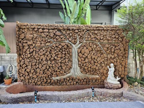 a stone wall with a tree and a statue at Dusita Residence in Bangkok