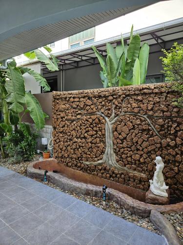 a stone wall with a tree sculpture on it at Dusita Residence in Bangkok