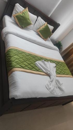 a bed with a green and white comforter on it at 3 bhk near lulu mall kochi in Cochin
