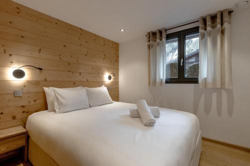 - une chambre avec un grand lit blanc et un mur en bois dans l'établissement Jardin du Brevent, à Chamonix-Mont-Blanc