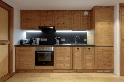 une cuisine avec des armoires en bois et un évier dans l'établissement Jardin du Brevent, à Chamonix-Mont-Blanc