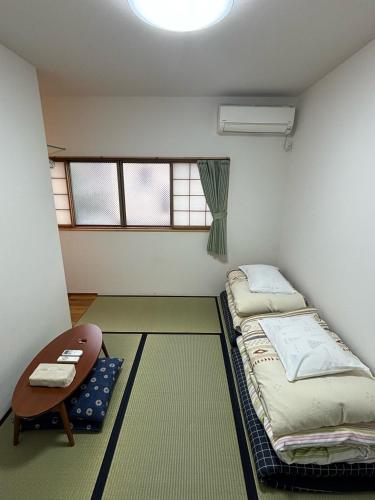a room with two beds and a table and windows at Kanazawa Guesthouse Stella in Kanazawa