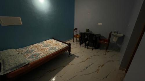 a bedroom with a bed and a table and chairs at Olive Homestays in Varkala