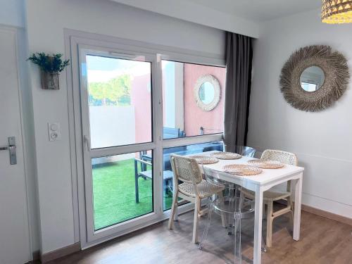 une salle à manger avec une table et des chaises et une fenêtre dans l'établissement T2 Cosy centre ville, parking privé, à La Grande Motte