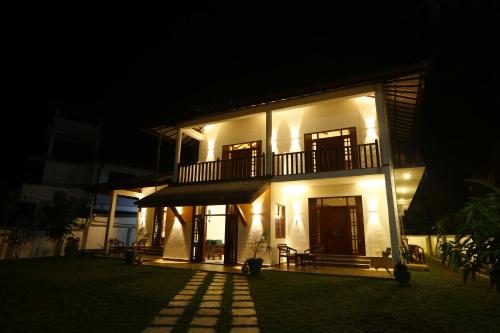 a large white building with a balcony at night at Lila Lodge, Villa - Bentota in Bentota