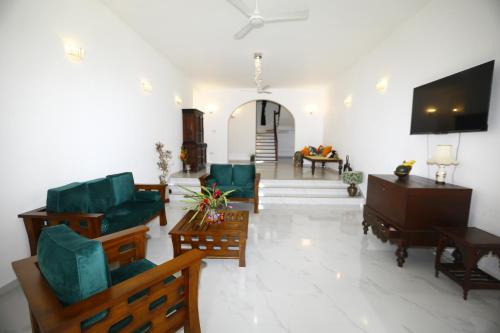 a living room with green furniture and a flat screen tv at Lila Lodge, Villa - Bentota in Bentota