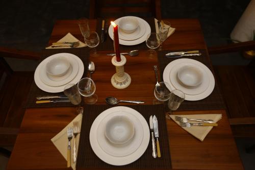 a wooden table with white plates and a candle on it at Lila Lodge, Villa - Bentota in Bentota