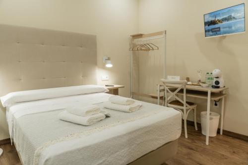 a white room with a bed with towels on it at Pensión María Castaña in Puebla del Brollón